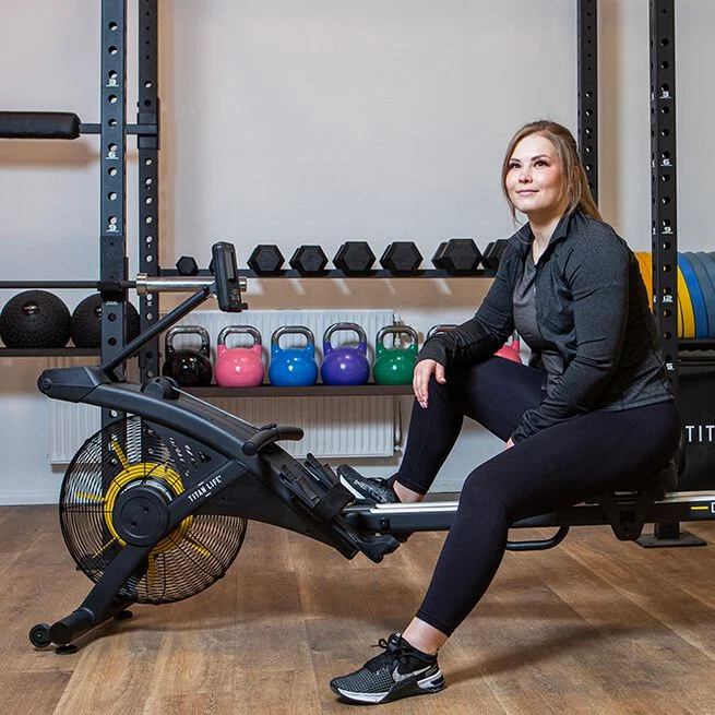 En tjej som sitter på en roddmaskin på gymmet