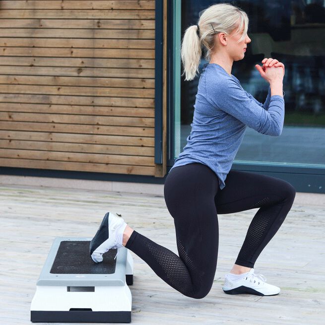 En tjej som tränar utfallssteg på en step up bräda