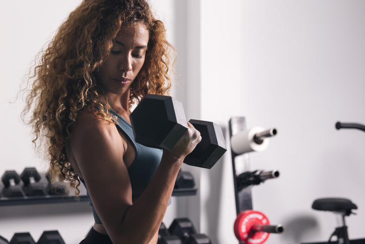 En kvinna som tränar styrketräning, här gör hon övningen bicepcurls