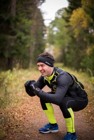 En kille som gör benböj utomhus med en viktväst