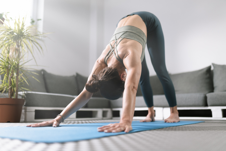 En kvinna som övar yoga hemma på en yogamatta