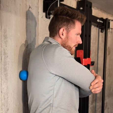 En man som behandlar en triggerpunkt på ryggen med en massageboll