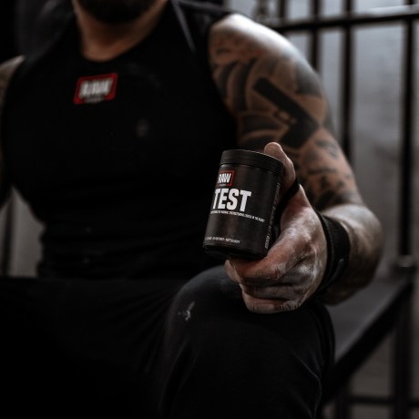 En man på gymmet med en testobooster i handen