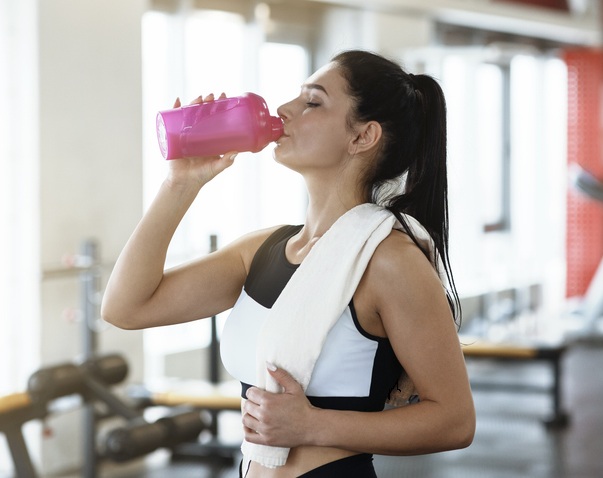 En kvinna som dricker en shake med sojaproteinpulver på gymmet
