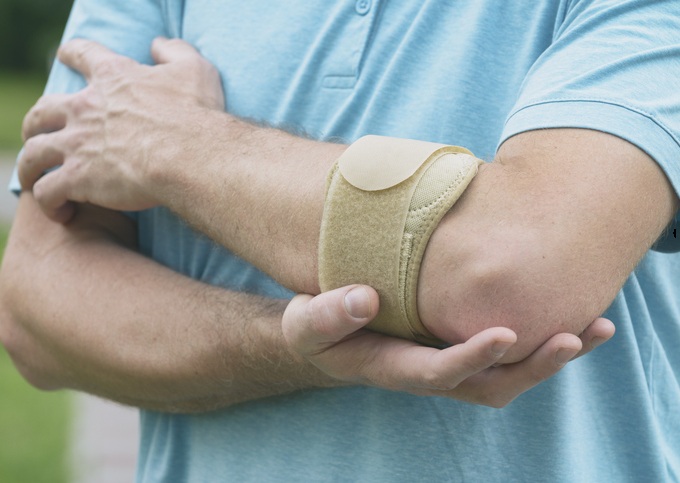 En man som har ett tennisarmbåge skydd